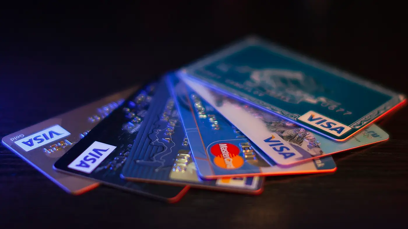 A fan of Visa and Mastercard payment cards lying on a dark table