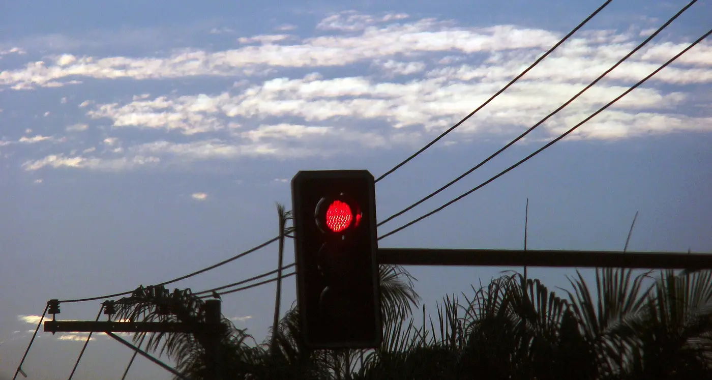 A red traffic light against an evening sky with power lines